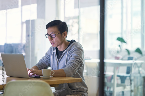 Photography Portrait of Asian businessman working on computer in office, backlit by natural