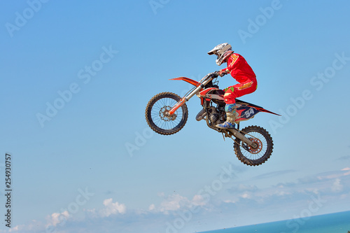 Extreme sports background - silhouette of biker jumping on motorbike on sunset, against the blue sky with clouds
