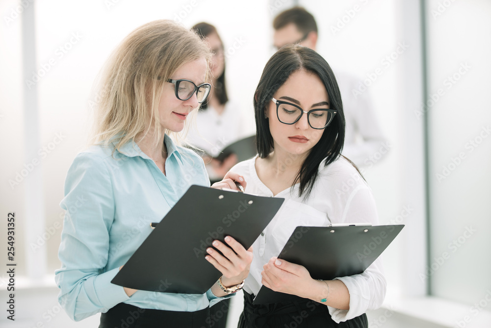 two business women discussing business documents standing in the office. two business women discussing business documents standing in the office.