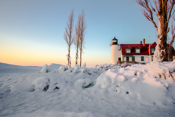 Winter Lighthouse On The Great Lakes. Beautiful winter landscape on the  coast of Lake Michigan with the Point Betsie Lighthouse bathed in the glow of the setting sun.