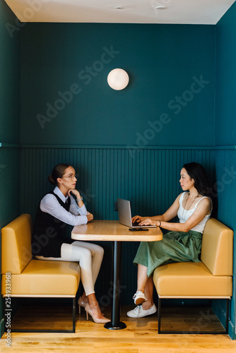 Foto Two delightful women talking about an archive inside a bistro