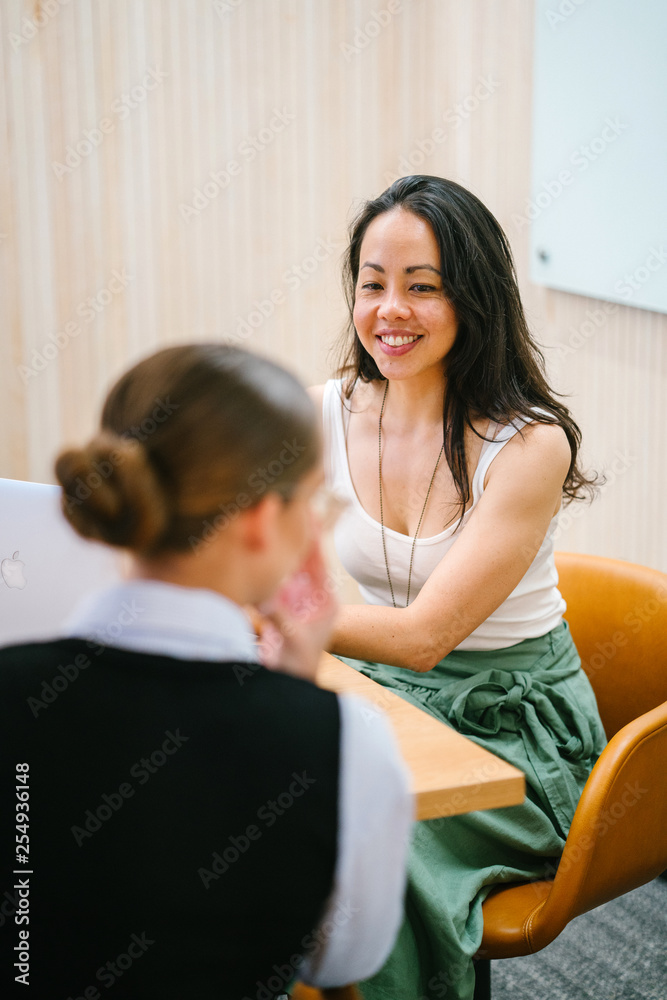 Two wonderful ladies discussing a story inside a room. They look extremely proficient in their office clothing.