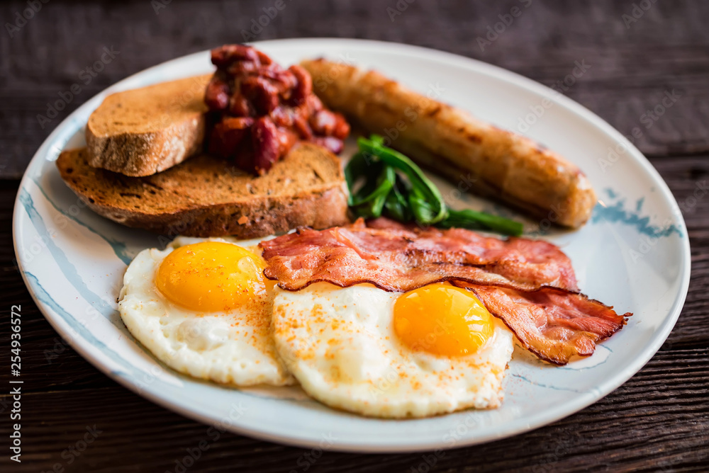 Typial breakfast with eggs, bacon and sausage on plate