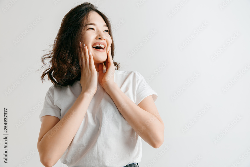 Happy asian woman standing and smiling isolated on gray studio background. Beautiful female half-length portrait. Young emotional woman. The human emotions, facial expression concept. Happy asian woman standing and smiling isolated on gray studio background. Beautiful female half-length portrait. Young emotional woman. The human emotions, facial expression concept.