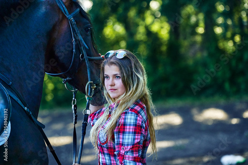 Beautiful girl with long hair on a walk with a horse. Summer evening.