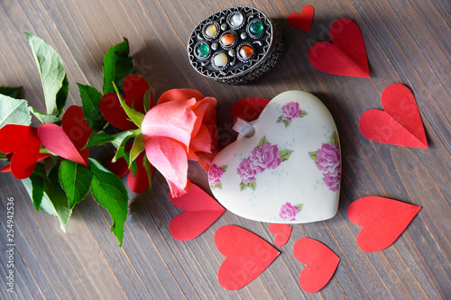 Porcelain heart on the wood table with flower and paper heart. photo