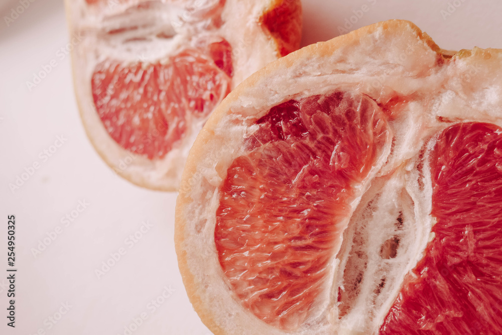 Halved grapefruit close up. Citrus fruit. Healthy eating. Pink color wallpaper. White background Halved grapefruit close up. Citrus fruit. Healthy eating. Pink color wallpaper. White background