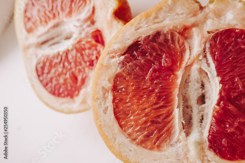 Halved grapefruit close up. Citrus fruit. Healthy eating. Pink color wallpaper. White background