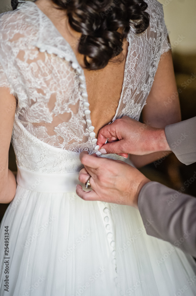 Mom's hands tie the bride's dress