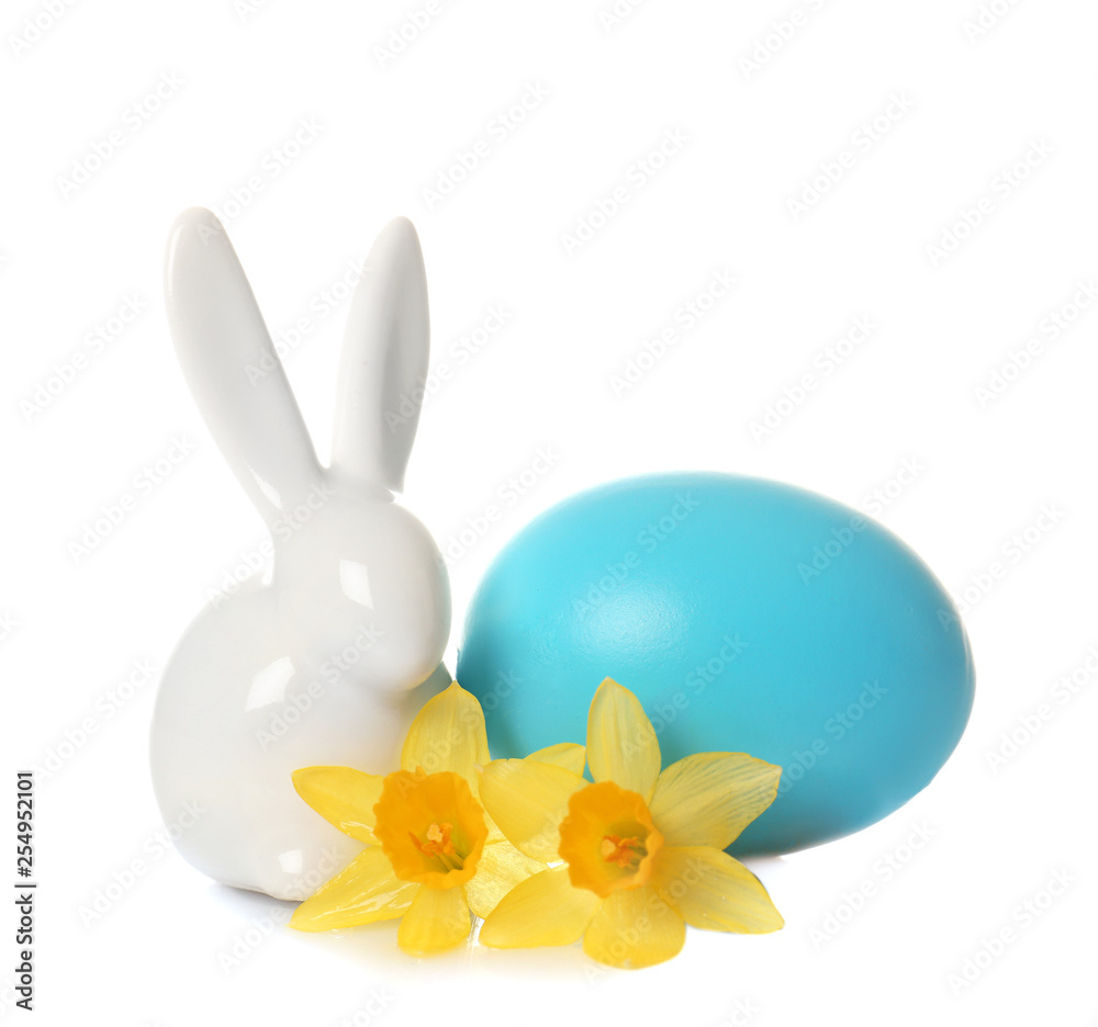 Cute ceramic Easter bunny with flower and dyed egg on white background Cute ceramic Easter bunny with flower and dyed egg on white background