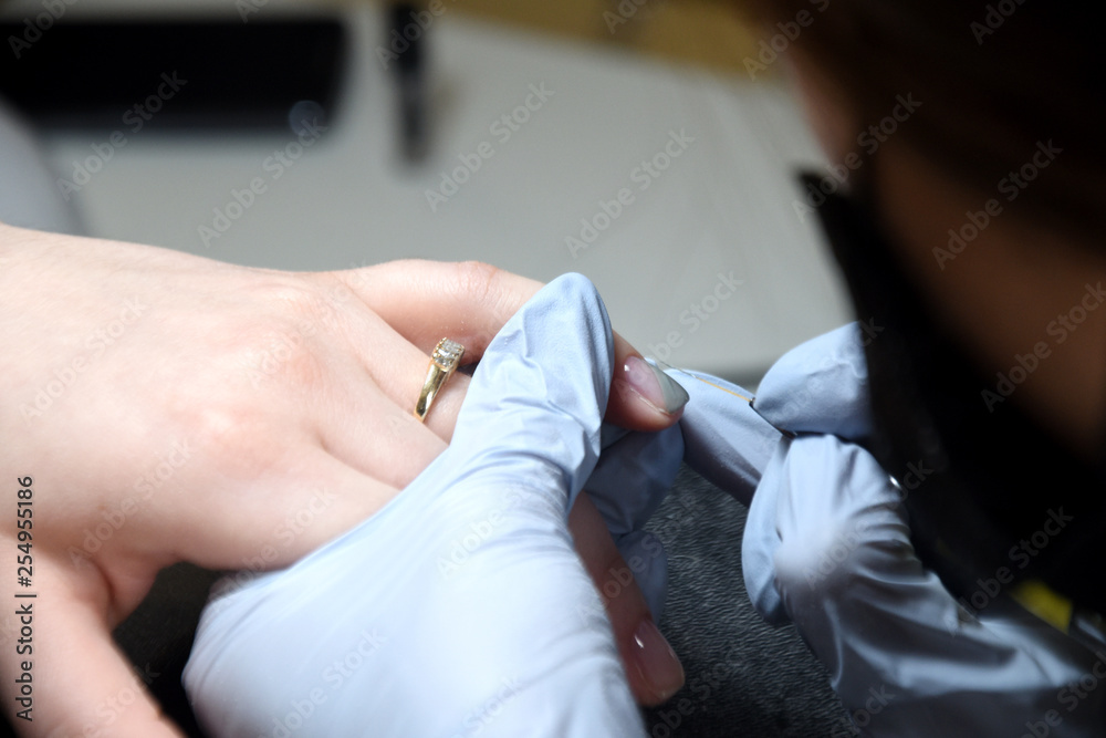 Fototapeta premium The master makes a manicure. Relaxing day at beauty salon. Manicurist master makes manicure on woman's hand. Girl paint nails, color gel nail Polish finger in nail salon