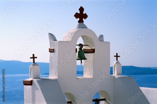 Fotografie Church tower with bell and crosses with Sea of the Caldera in distance, Oia, San