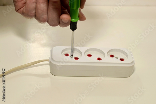 Electrician using a screwdriver repairing an electrical extension cord