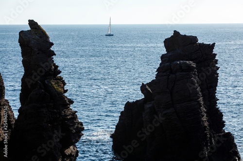 Barca a vela in lontananza  in mezzo agli scogli - Calasetta - Sardegna photo