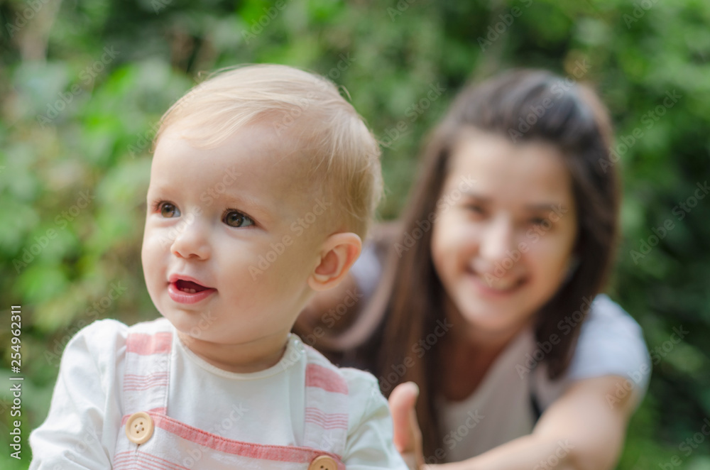Beautiful brunette female in straw hat jeans, white t-shirt and a small backpack with his little cute child daughter playing together in a park Beautiful brunette female in straw hat jeans, white t-shirt and a small backpack with his little cute child daughter playing together in a park