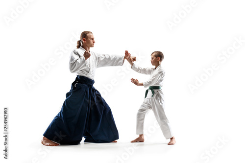 Man and teen boy fighting at Aikido training in martial arts school. Healthy lifestyle and sports concept. Fightrers in white kimono on white background. Karate men with concentrated faces in uniform.