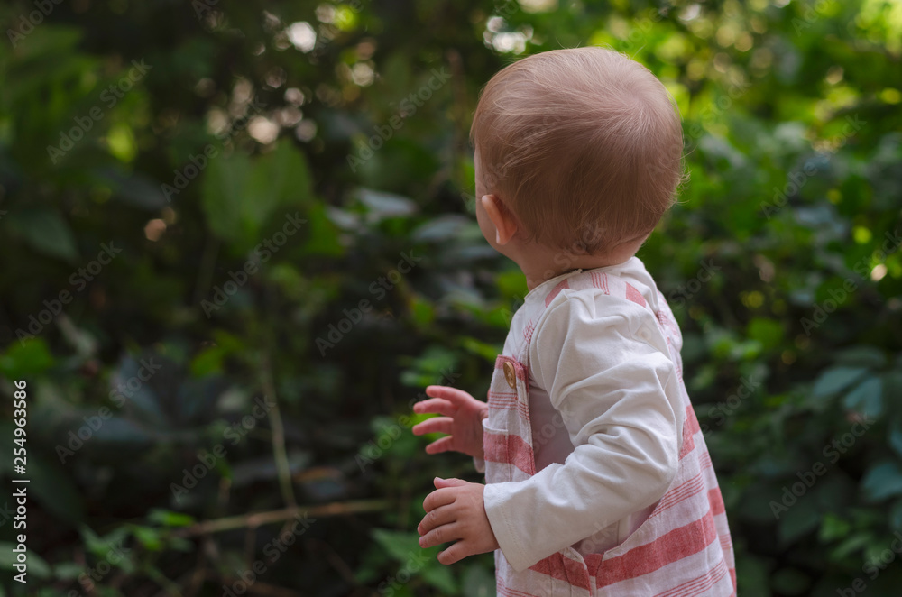 Beautiful brunette female in straw hat jeans, white t-shirt and a small backpack with his little cute child daughter playing together in a park Beautiful brunette female in straw hat jeans, white t-shirt and a small backpack with his little cute child daughter playing together in a park