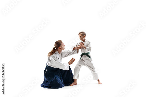 Man and teen boy fighting at Aikido training in martial arts school. Healthy lifestyle and sports concept. Fightrers in white kimono on white background. Karate men with concentrated faces in uniform. © master1305