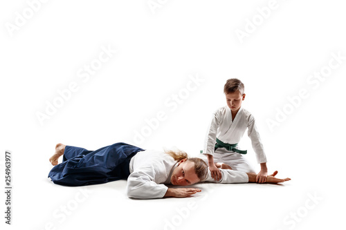 Man and teen boy fighting at Aikido training in martial arts school. Healthy lifestyle and sports concept. Fightrers in white kimono on white background. Karate men with concentrated faces in uniform.