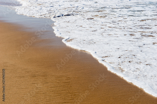 Beach sea sand with a soft wave of surf. Beach background