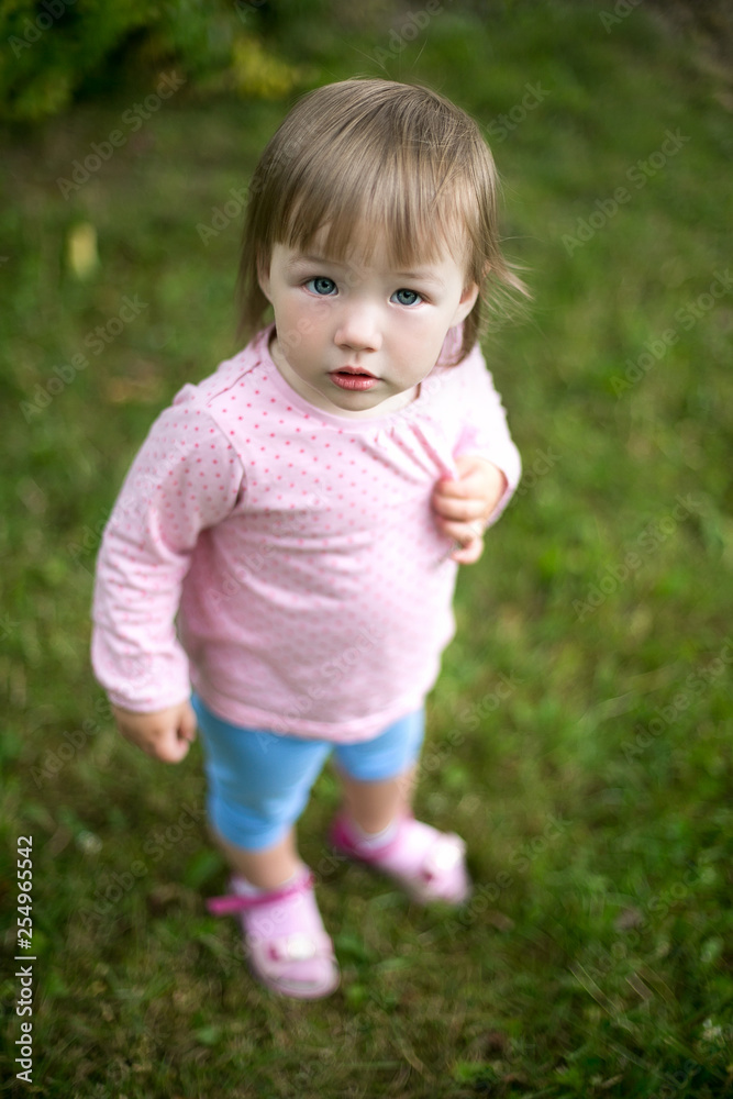 Cute little infant baby girl outdoors in green summer park Cute little infant baby girl outdoors in green summer park
