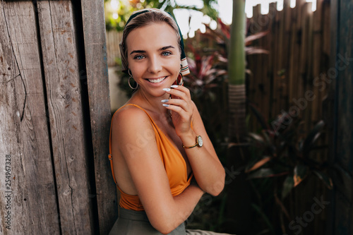 Charming lovely european woman in trend outfit with tanned skin smiling to camera and enjoying summer day in tropics 