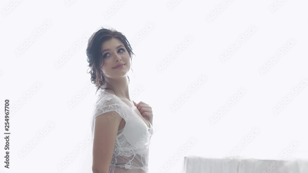 slow motion pretty bride in white transparent lacy underwear with purple bouquet smiles against window slow motion pretty bride in white transparent lacy underwear with purple bouquet smiles against window