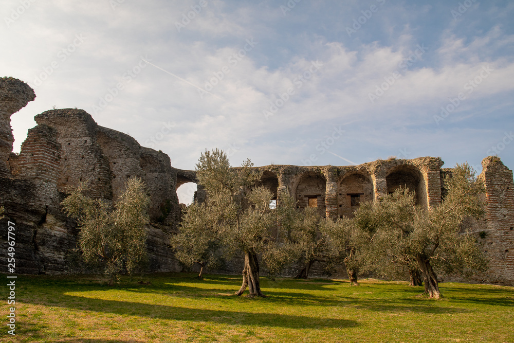 The Grottoes of Catullo, the ruins of a Roman villa built at the end of the 1st century B.C. on the shore of Lake Garda, with olive trees and green lawn in springtime, Sirmione, Lombardy, Italy