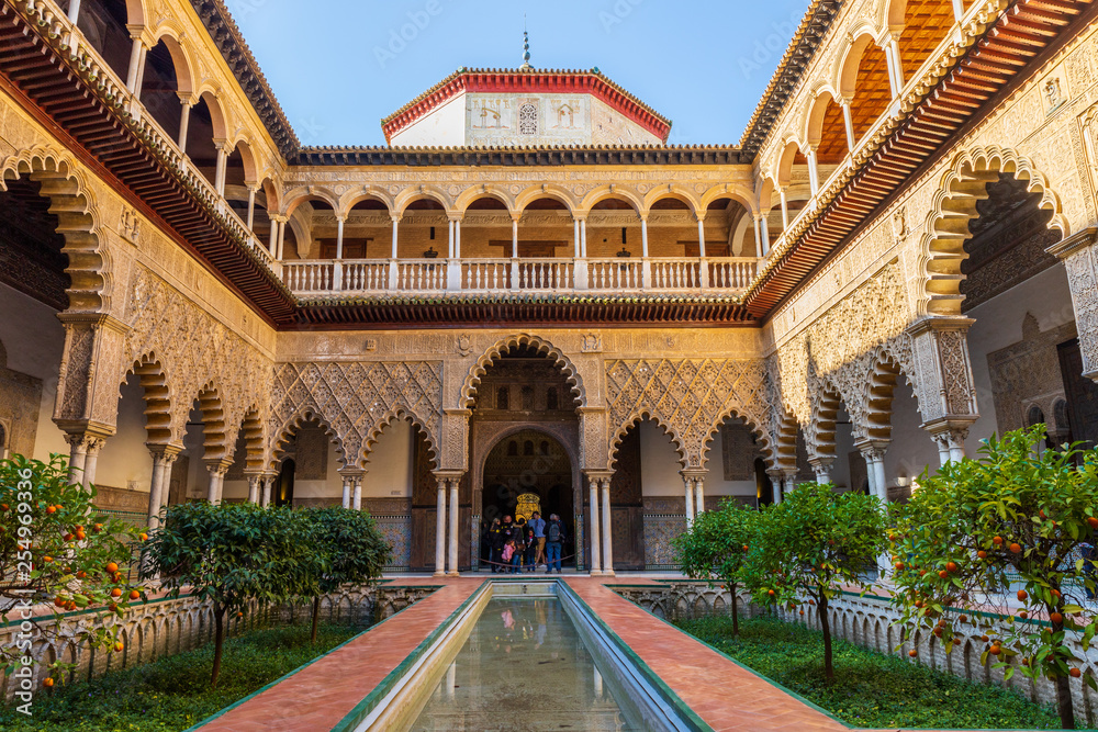 Fototapeta premium Seville / Spain: Tourists in the yard of Real Alcazar Royal Palace - March 2019