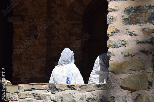 Weiss verhüllte Gläubige geht in die dunkle Kirche photo