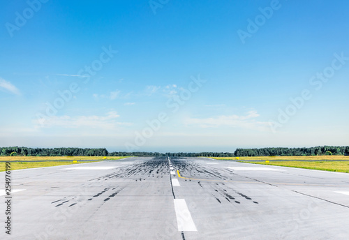 Empty runway at the airport on a sunny clear cloudless day.
