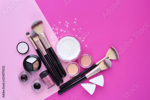 Makeup brush and decorative cosmetics on pink background. Top view