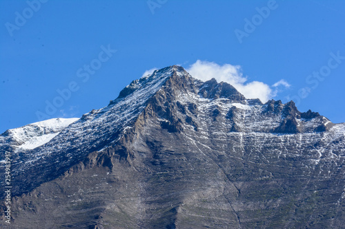 Berggipfel vor  blauen Himmel mit Wolken mit Schnee