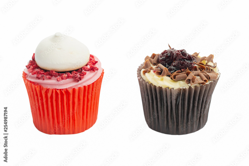 Cupcake in red paper case with pink frosting and raspberry on top and chocolate black forest fairy cake on white, selective focus Cupcake in red paper case with pink frosting and raspberry on top and chocolate black forest fairy cake on white, selective focus