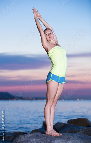 woman in sportwear doing exercises at sunset sea shore