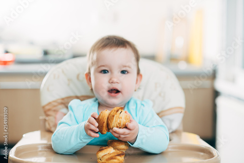 the little girl in the highchair in the hands Krapina  like muffins and croissants trend 2019