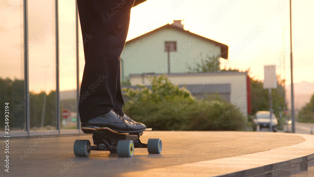 CLOSE UP: Unrecognizable yuppie going home from work on his electric skateboard CLOSE UP: Unrecognizable yuppie going home from work on his electric skateboard