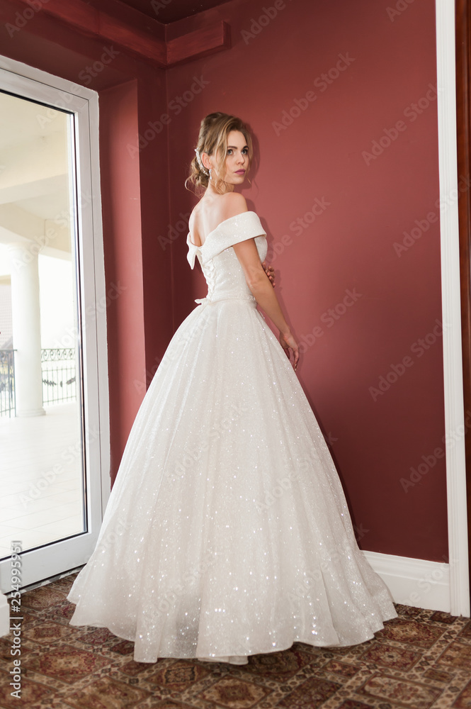 Portrait of a beautiful bride woman in elegant white wedding dress. Luxurious apartments. 