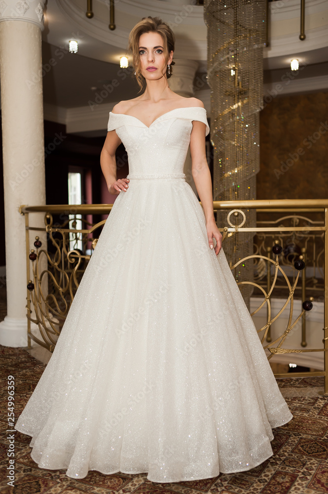 Fototapeta premium Portrait of a beautiful bride woman in elegant white wedding dress. Luxurious apartments. 