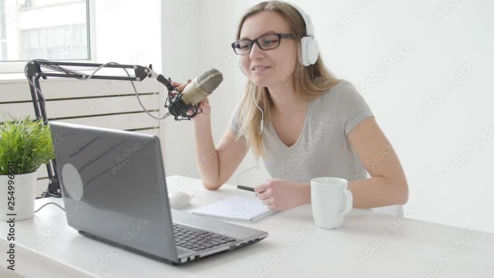 Concept of streaming and broadcasting. Young cheerful girl in the studio speaks into a microphone Concept of streaming and broadcasting. Young cheerful girl in the studio speaks into a microphone