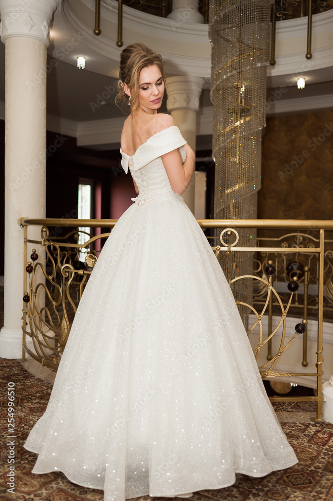 Naklejka premium Portrait of a beautiful bride woman in elegant white wedding dress. Luxurious apartments. 