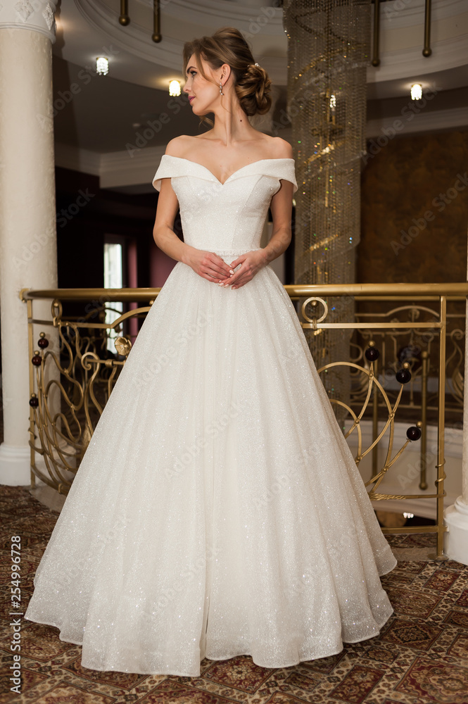 Fototapeta premium Portrait of a beautiful bride woman in elegant white wedding dress. Luxurious apartments. 