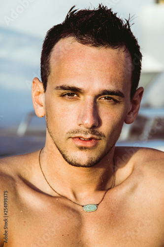 Portrait of a handsome young man in the swimming pool. Perfect hair & skin. Outdoor shot.