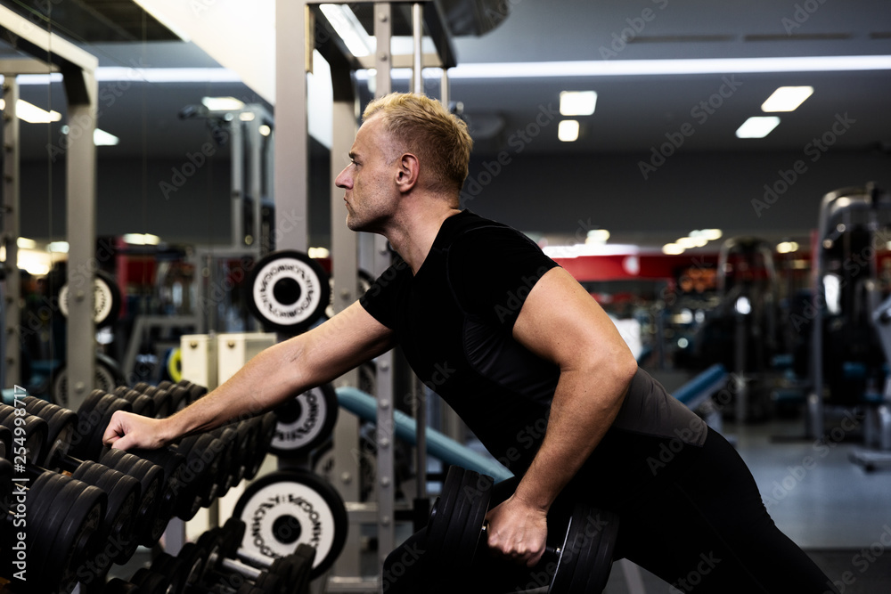 Young man doing the exercises with dumbbell at biceps for good body in fitness gym, bodybuilder, healthy lifestyle, exercise fitness, workout and sport training concept Young man doing the exercises with dumbbell at biceps for good body in fitness gym, bodybuilder, healthy lifestyle, exercise fitness, workout and sport training concept