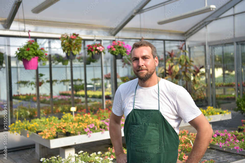 Portrait Gärtner im Gewächshaus mit bunten Blumen einer Gärtnerei