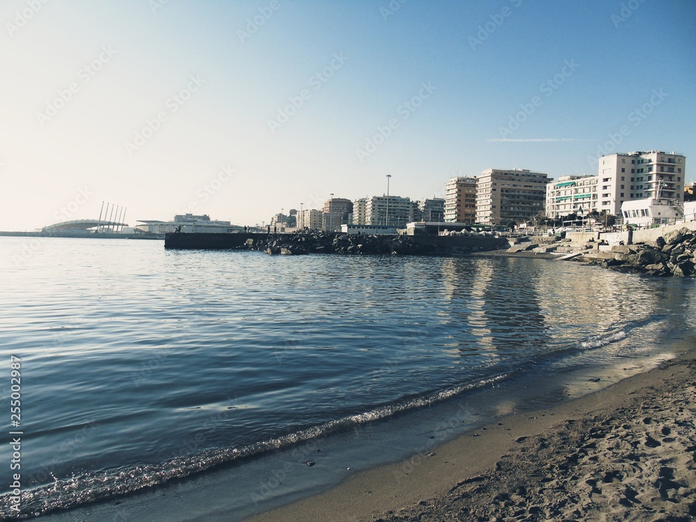 Genova, Italy - 03/08/2019: An amazing caption of small waves and beautiful sunset with an incredible reflection over the sea and some coloured clouds in winter days, and some black and white photos.