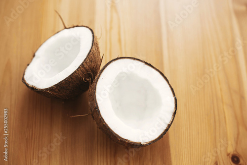 Halved coconut on wooden table, flat lay. Hello summer vacation concept. Space for text. Tropical background with coconut. Delicious nut, refreshing drink and oil source, tasty milk