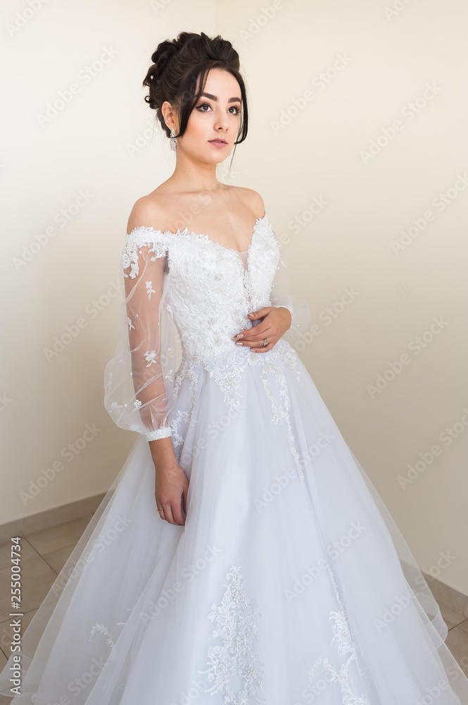 Beautiful bride wearing fashion wedding dress with feathers with luxury delight make-up and hairstyle studio indoor photo shoot Beautiful bride wearing fashion wedding dress with feathers with luxury delight make-up and hairstyle studio indoor photo shoot