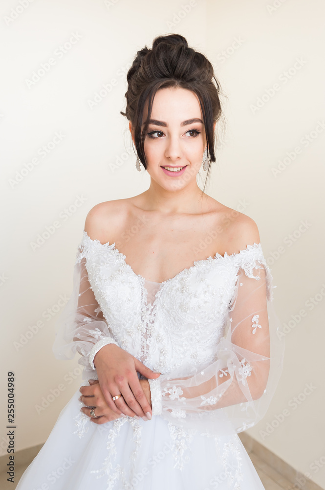 Beautiful bride wearing fashion wedding dress with feathers with luxury delight make-up and hairstyle  studio indoor photo shoot