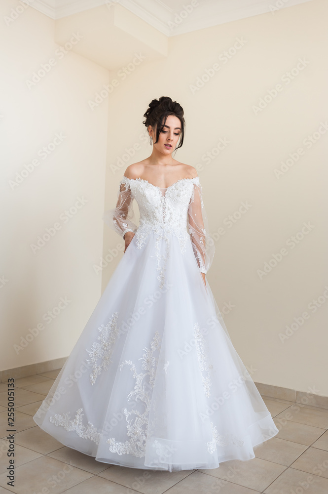 Beautiful bride wearing fashion wedding dress with feathers with luxury delight make-up and hairstyle  studio indoor photo shoot